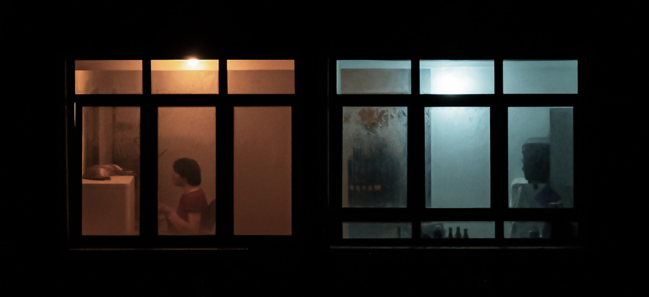 Two adjacent windows illuminated with warm and cool light on a building in Tel Aviv, Israel.