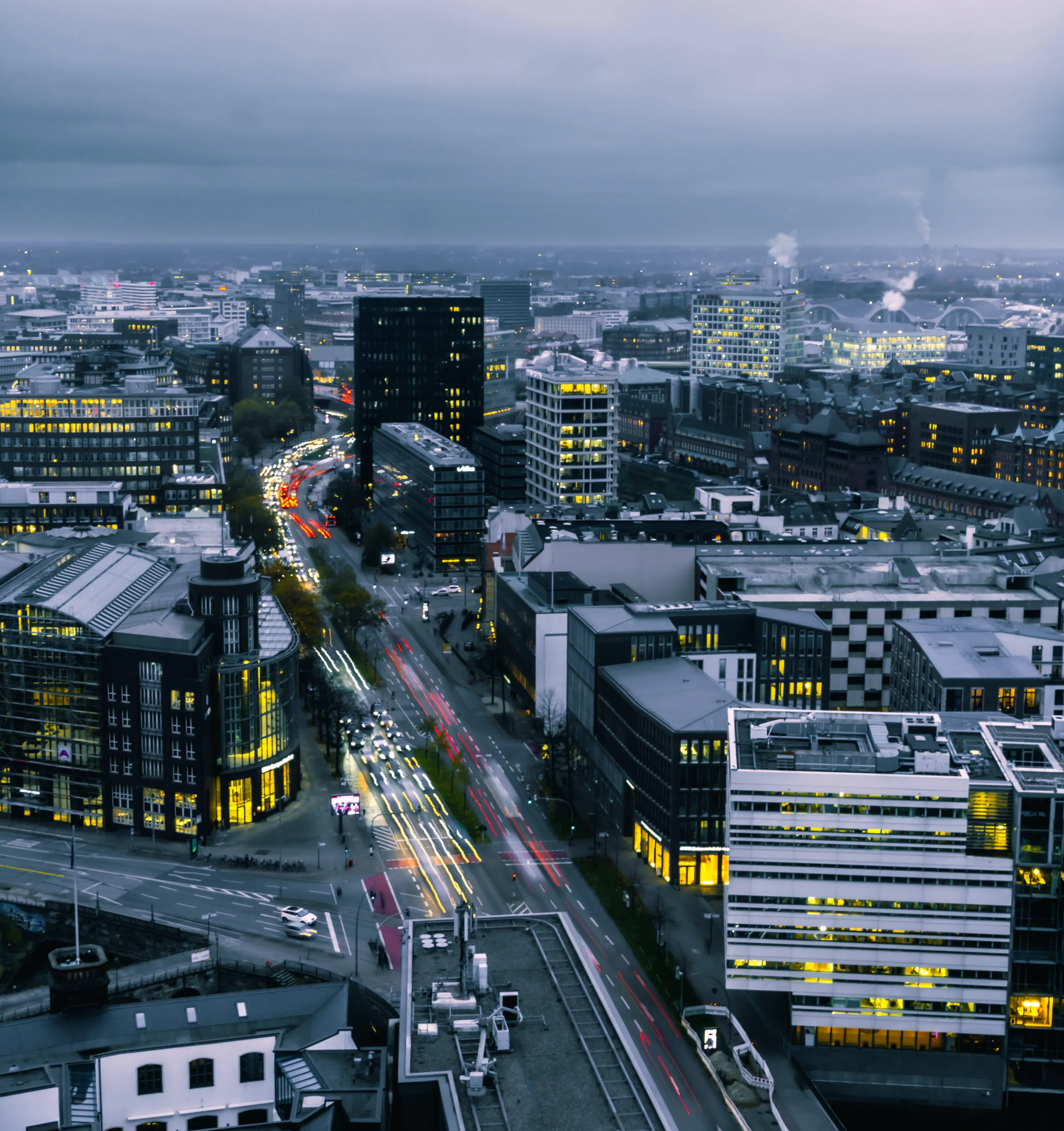 Long-exposure view of Hamburg at dusk with light trails beneath a cloudy sky.