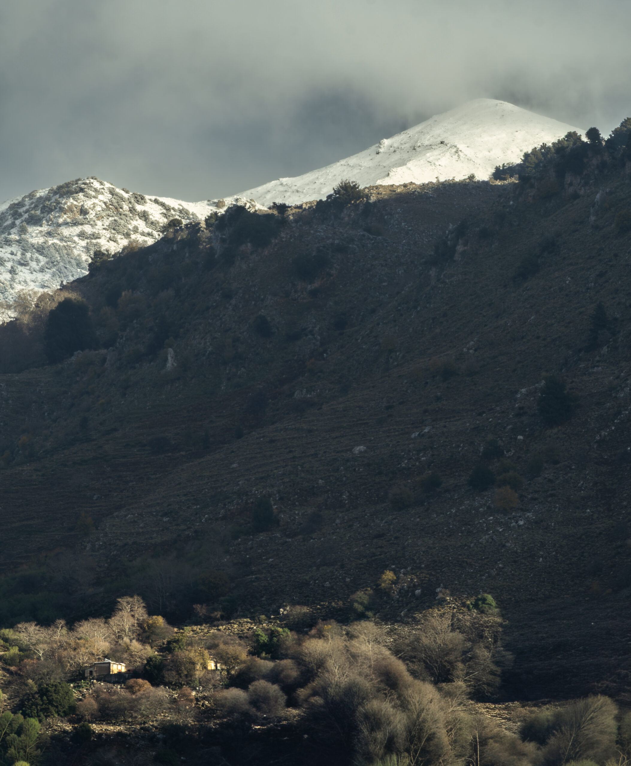 Sunlight illuminating the snow-covered Lefká Ori after a break in the clouds, Crete, Greece.