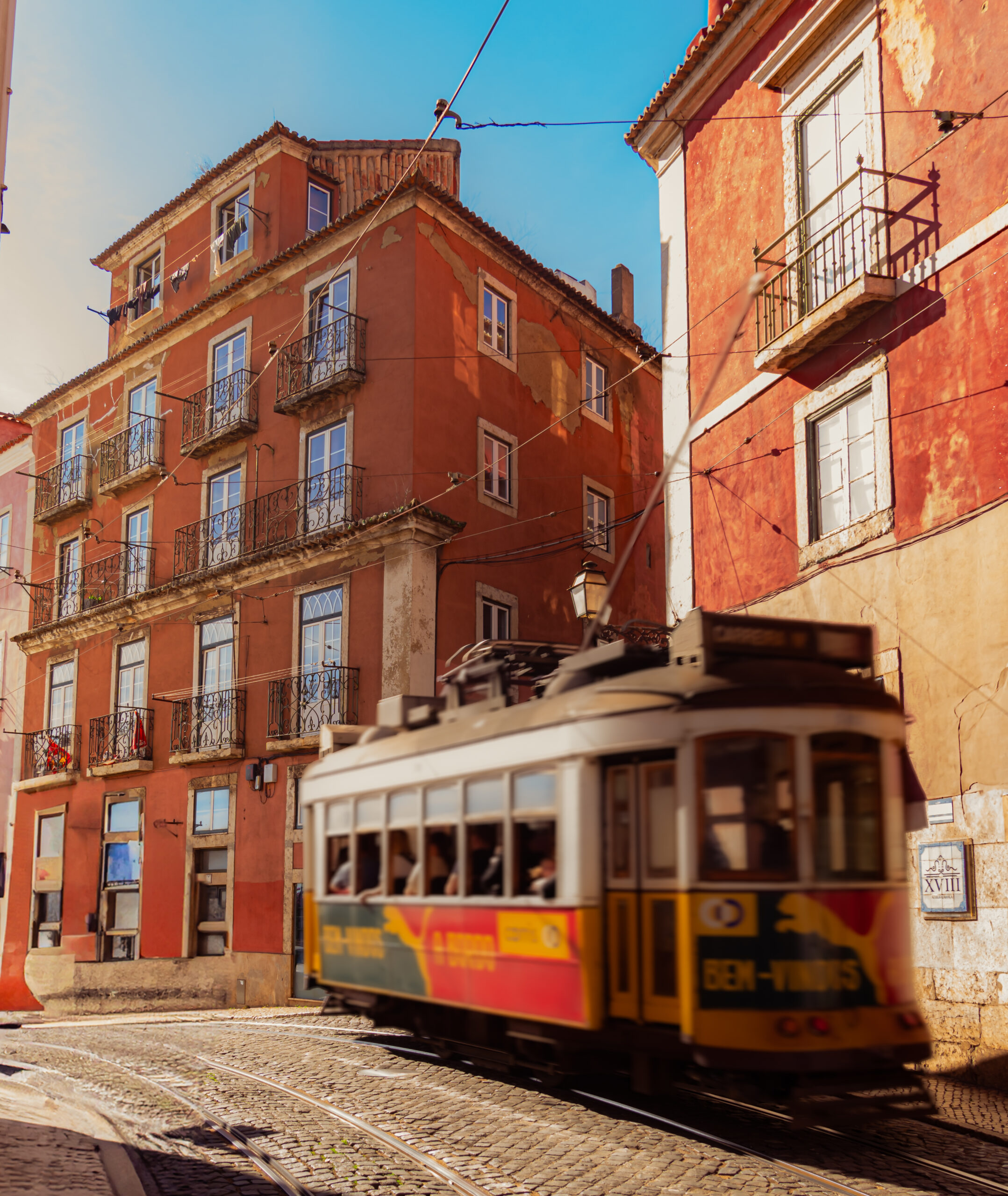 Iconic yellow tram rounding a corner in the historic streets of Lisbon, Portugal.