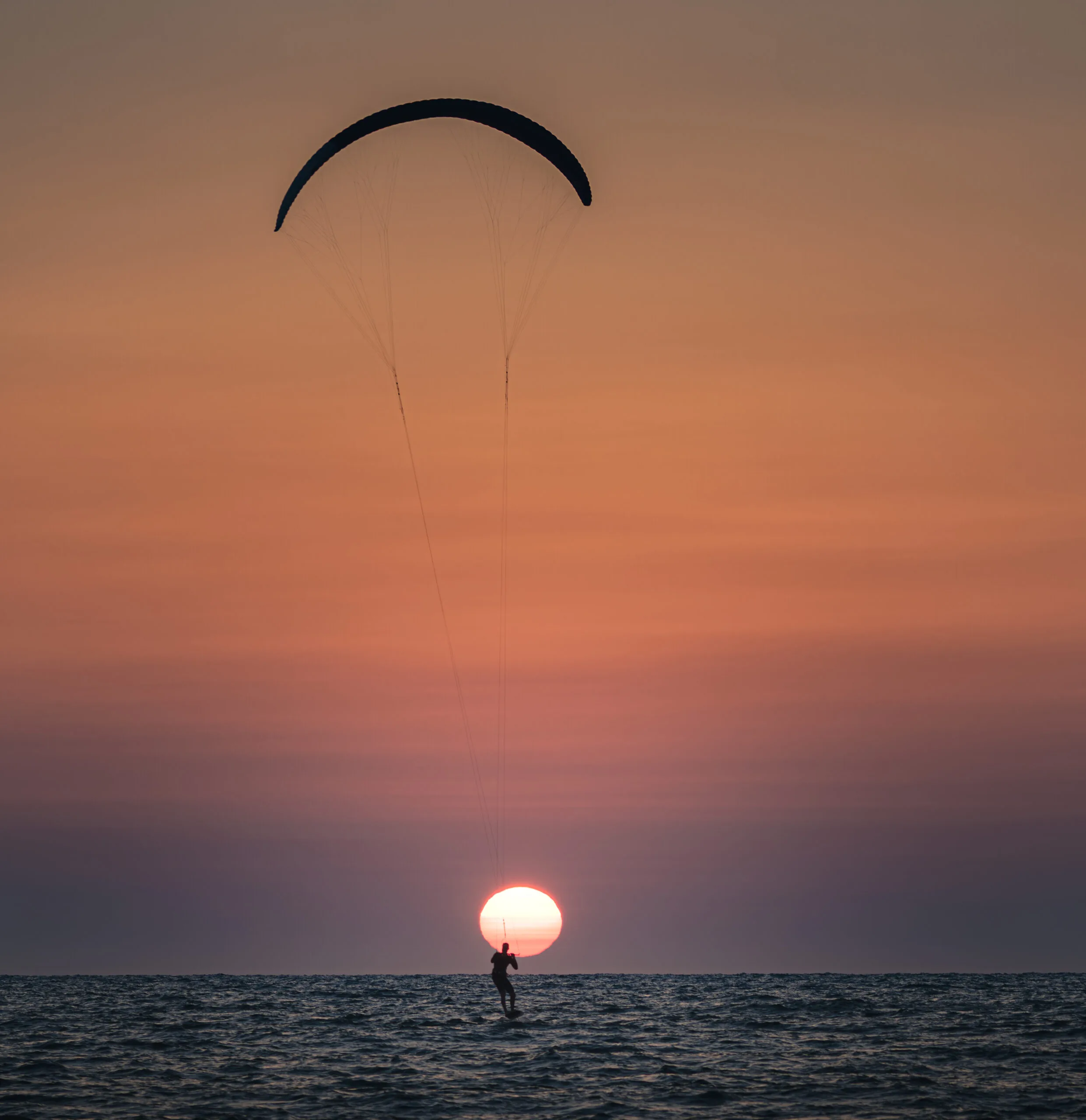 Kitesurfer silhouetted against the setting sun over the Mediterranean in Tel Aviv, Israel.